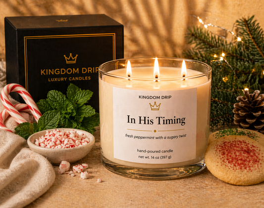 Kingdom Drip candle labeled 'In His Timing' with holiday decorations on a wooden surface.