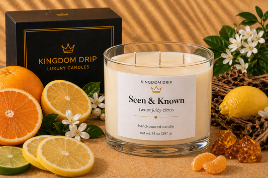 Kingdom Drip candle labeled 'Seen & Known' with citrus fruits and flowers on a wooden surface