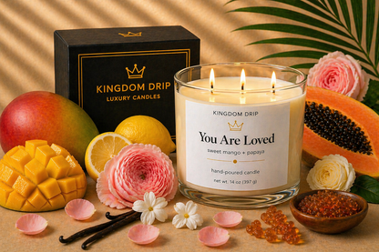 Kingdom Drip candle labeled 'You Are Loved' with fruits, flowers, and a box in the background.